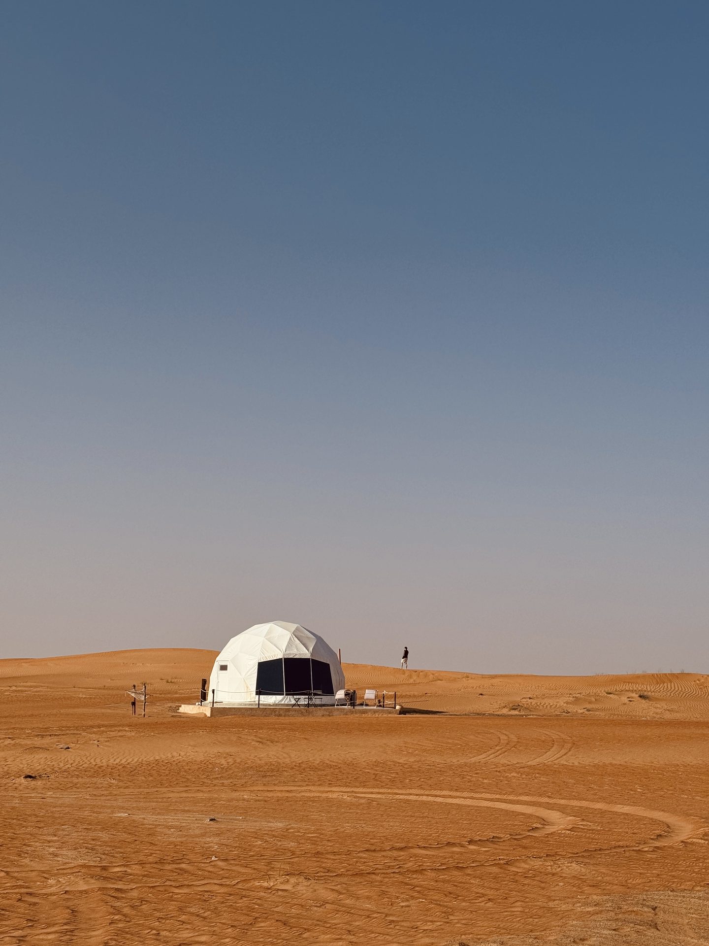 A lone desert dome camp on the dunes under a wide sky