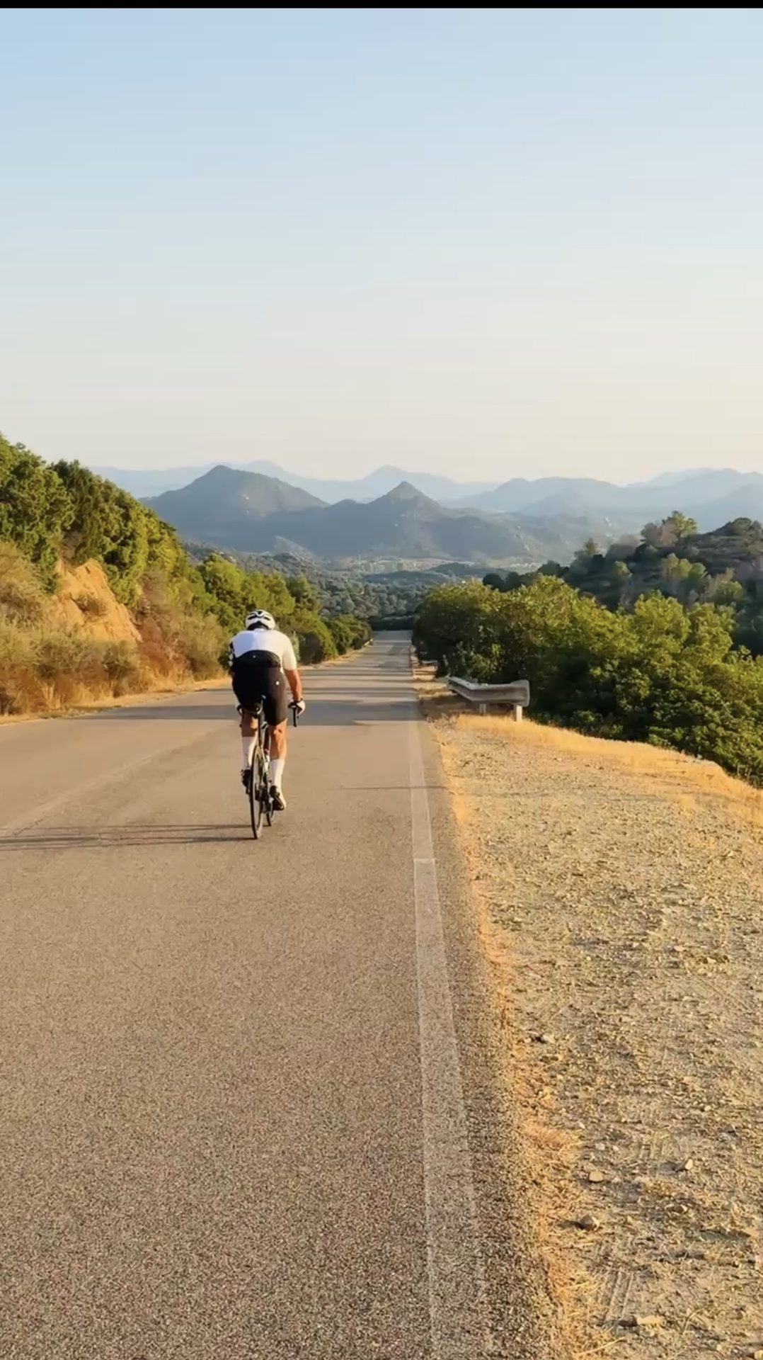 A cyclist on an open mountain road at golden hour